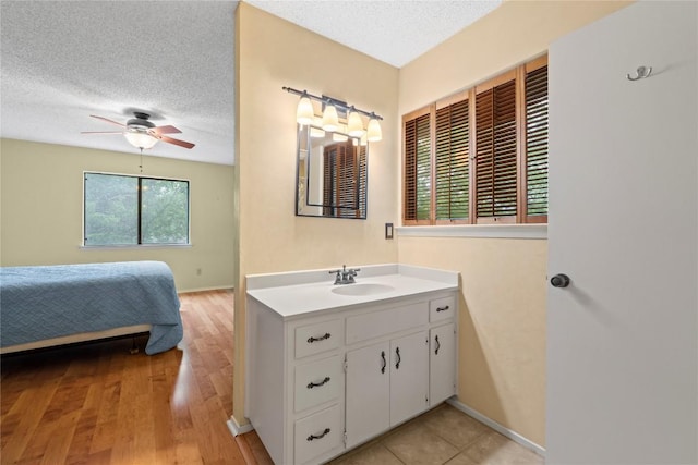 11708 Barrington Way, Austin, TX 78759 - ensuite bathroom featuring vanity, a textured ceiling, ceiling fan, wood finished floors, and baseboards