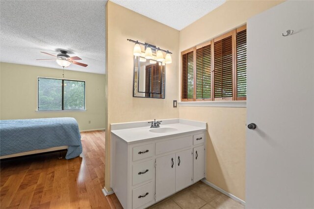 11708 Barrington Way, Austin, TX 78759 - bathroom featuring vanity, ceiling fan, a textured ceiling, wood finished floors, and ensuite bath