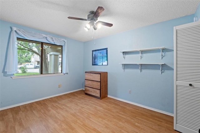 11708 Barrington Way, Austin, TX 78759 - unfurnished bedroom featuring light wood finished floors, a textured ceiling, baseboards, and a closet