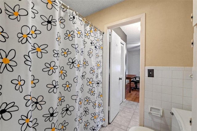 11708 Barrington Way, Austin, TX 78759 - bathroom with tile walls, tile patterned flooring, curtained shower, a wainscoted wall, and a textured ceiling