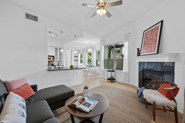 2216 Thornton Rd Unit 221, Austin, TX 78704 - living area featuring light wood-style flooring, ceiling fan, a tiled fireplace, and vaulted ceiling