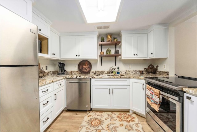 1135 Barton Hills Dr Unit 160, Austin, TX 78704 - kitchen featuring stainless steel appliances, a sink, white cabinetry, light stone countertops, and light wood-style floors