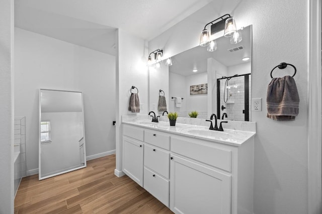 2545 Belle Hubbard Trl, Belton, TX 76513 - full bathroom featuring double vanity, wood finished floors, tiled shower, and baseboards