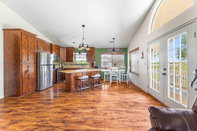 178 Balch Rd, Elgin, TX 78621 - kitchen with appliances with stainless steel finishes, vaulted ceiling, light countertops, a kitchen breakfast bar, and dark wood-type flooring