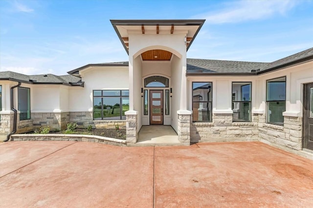 178 Balch Rd, Elgin, TX 78621 - property entrance featuring stone siding, stucco siding, a shingled roof, and a patio area