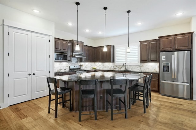 192 Call Dr, Austin, TX 78737 - kitchen featuring stainless steel appliances, dark brown cabinetry, light wood-style flooring, a center island, and backsplash