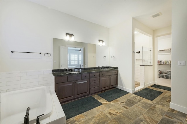 192 Call Dr, Austin, TX 78737 - full bath featuring a garden tub, tiled shower, double vanity, stone finish floors, and baseboards