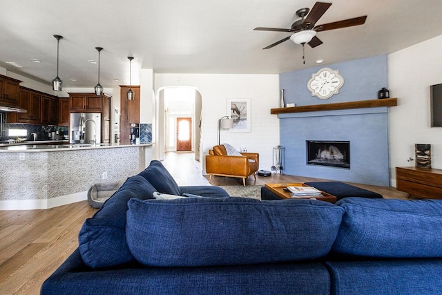 110 Saint Richie Ln, Austin, TX 78737 - living room with arched walkways, a ceiling fan, light wood-style flooring, and a fireplace