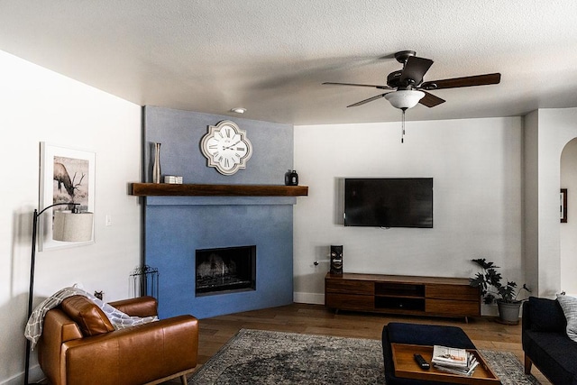 110 Saint Richie Ln, Austin, TX 78737 - living area featuring ceiling fan, wood finished floors, a fireplace, arched walkways, and baseboards
