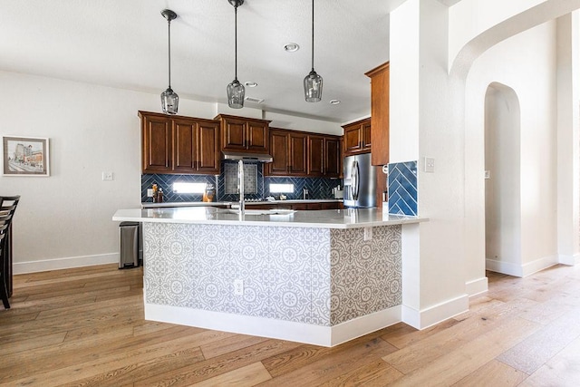 110 Saint Richie Ln, Austin, TX 78737 - kitchen featuring stainless steel refrigerator with ice dispenser, arched walkways, light wood-style flooring, light countertops, and decorative backsplash