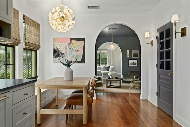 1712 Hartford Rd, Austin, TX 78703 - dining space with arched walkways, a chandelier, dark wood-style floors, and baseboards