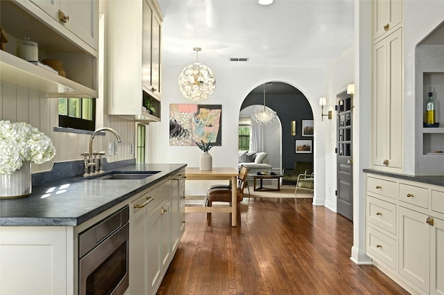 1712 Hartford Rd, Austin, TX 78703 - kitchen featuring open shelves, a sink, dark countertops, dark wood finished floors, and arched walkways