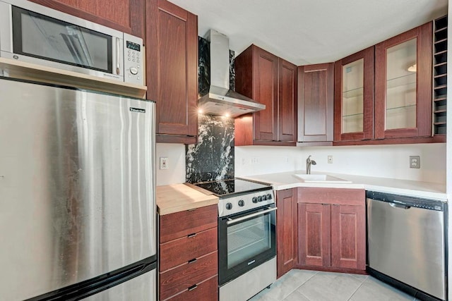1840 Burton Dr Unit 102, Austin, TX 78741 - kitchen with stainless steel appliances, wall chimney range hood, a sink, light countertops, and glass insert cabinets
