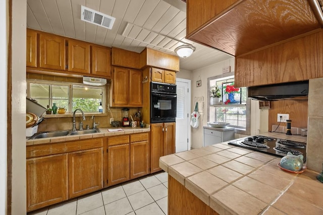 217 S Wilson St, San Marcos, TX 78666 - kitchen with tile countertops, black appliances, brown cabinets, and decorative backsplash