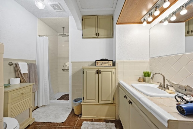 217 S Wilson St, San Marcos, TX 78666 - full bathroom with tiled shower, vanity, tile patterned floors, tile walls, and a wainscoted wall