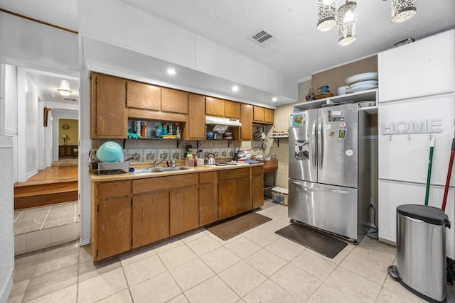 217 S Wilson St, San Marcos, TX 78666 - kitchen featuring stainless steel fridge with ice dispenser, brown cabinets, a sink, light countertops, and under cabinet range hood
