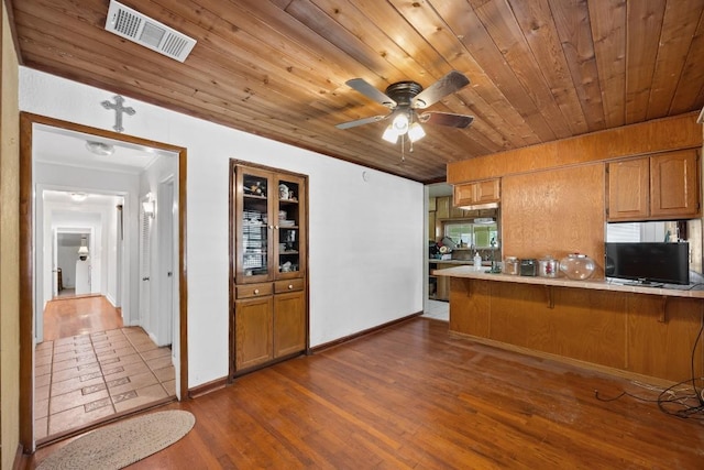 217 S Wilson St, San Marcos, TX 78666 - kitchen with brown cabinets, wooden ceiling, a kitchen bar, a peninsula, and dark wood-style flooring