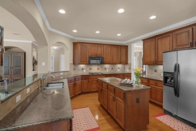 12709 Pinto Chase Ct, Austin, TX 78732 - kitchen with stainless steel appliances, arched walkways, a sink, brown cabinets, and ornamental molding