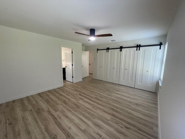 8527 Birmingham Dr, Austin, TX 78748 - unfurnished bedroom featuring wood finished floors, baseboards, a ceiling fan, and a barn door