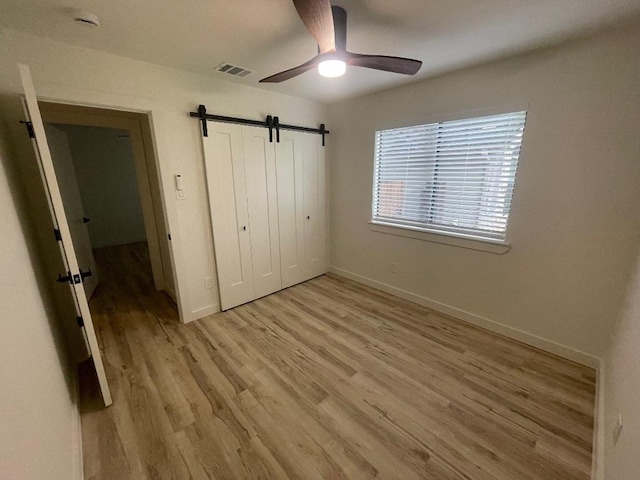 8527 Birmingham Dr, Austin, TX 78748 - unfurnished bedroom with light wood-style flooring, a closet, baseboards, a barn door, and a ceiling fan
