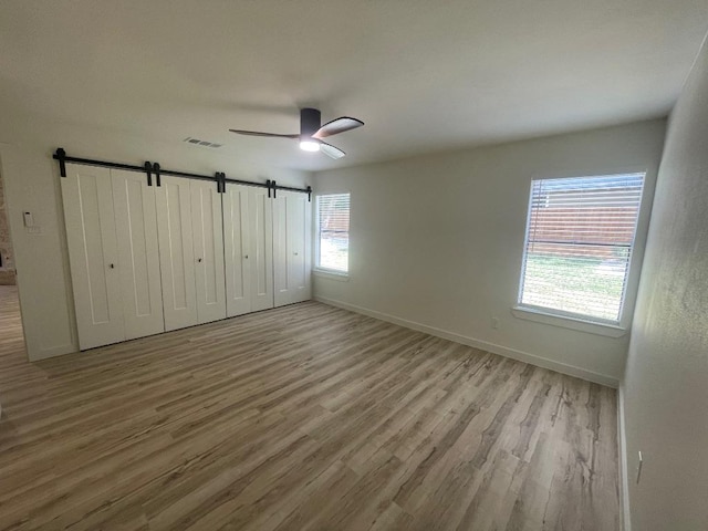 8527 Birmingham Dr, Austin, TX 78748 - unfurnished bedroom with wood finished floors, a barn door, and ceiling fan