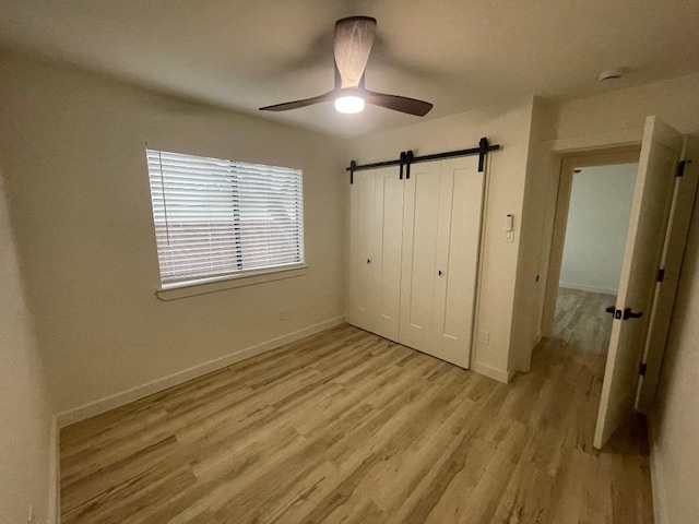 8527 Birmingham Dr, Austin, TX 78748 - unfurnished bedroom featuring light wood-style floors, baseboards, a closet, a barn door, and ceiling fan