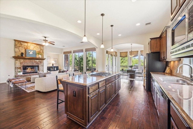 331 Littleton Dr, Austin, TX 78737 - kitchen featuring stainless steel appliances, arched walkways, a kitchen breakfast bar, light stone counters, and recessed lighting