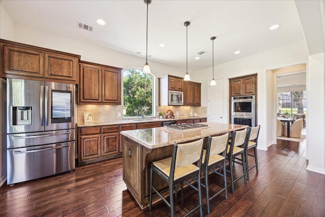 331 Littleton Dr, Austin, TX 78737 - kitchen with appliances with stainless steel finishes, dark wood finished floors, a breakfast bar area, a kitchen island, and recessed lighting