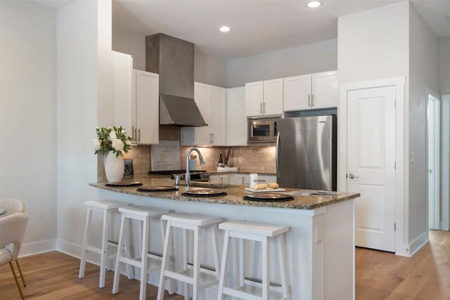 2520 Bluebonnet Ln Unit 58, Austin, TX 78704 - kitchen featuring appliances with stainless steel finishes, wall chimney exhaust hood, a peninsula, stone countertops, and white cabinets