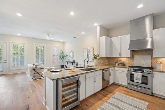 2520 Bluebonnet Ln Unit 58, Austin, TX 78704 - kitchen with stainless steel appliances, beverage cooler, wall chimney exhaust hood, a peninsula, and white cabinets