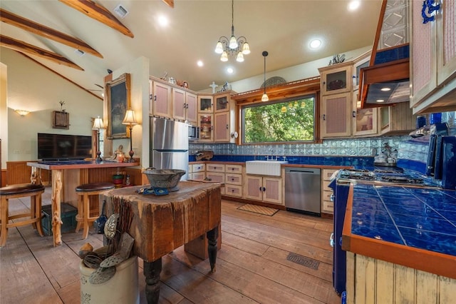 136 Red Fox Ln, Bastrop, TX 78602 - kitchen with appliances with stainless steel finishes, light wood-style flooring, decorative backsplash, tile counters, and hanging light fixtures