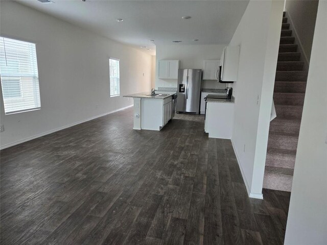 12324 Token Trl, Elgin, TX 78621 - unfurnished living room featuring dark wood finished floors, a sink, stairway, and baseboards