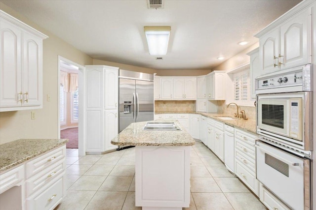 1204 Fairway Cir, Salado, TX 76571 - kitchen with built in refrigerator, white double oven, electric stovetop, a center island, and light stone counters