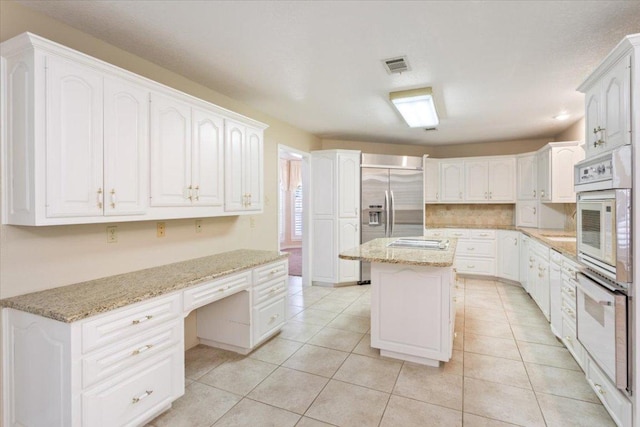 1204 Fairway Cir, Salado, TX 76571 - kitchen with built in refrigerator, white double oven, built in desk, and light stone counters