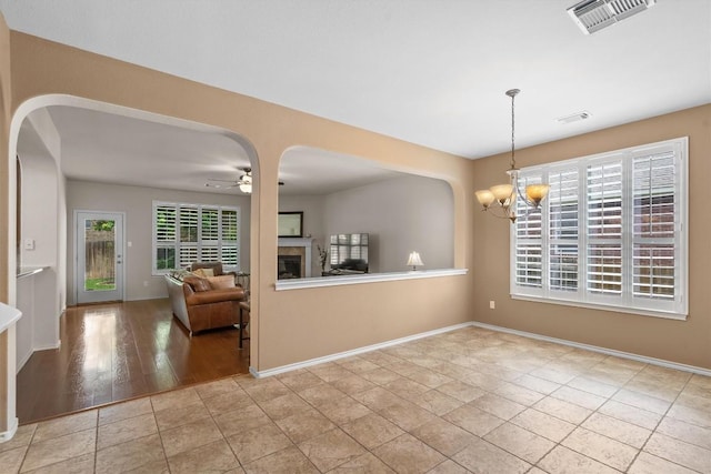 306 Water Oak Dr, Cedar Park, TX 78613 - unfurnished dining area featuring arched walkways, a chandelier, baseboards, a ceiling fan, and a glass covered fireplace