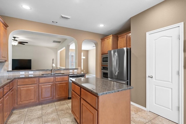 306 Water Oak Dr, Cedar Park, TX 78613 - kitchen with a sink, stainless steel appliances, arched walkways, brown cabinetry, and recessed lighting
