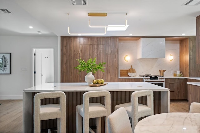 3403 Cascadera Dr, Austin, TX 78731 - kitchen featuring modern cabinets, high end range, light countertops, a breakfast bar, and brown cabinetry