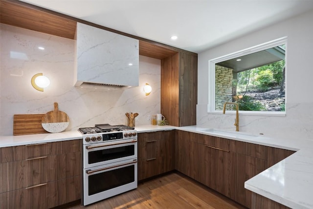 3403 Cascadera Dr, Austin, TX 78731 - kitchen featuring double oven range, modern cabinets, backsplash, wood finished floors, and extractor fan