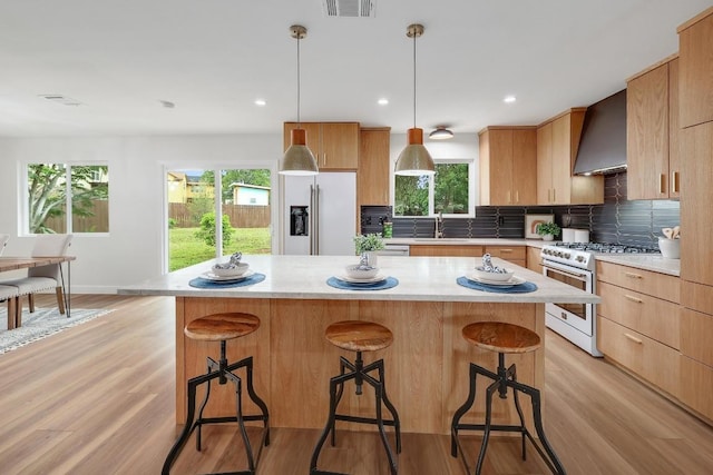 3812 Tarragona Ln, Austin, TX 78727 - kitchen featuring high end appliances, wall chimney exhaust hood, light countertops, light wood-style floors, and recessed lighting