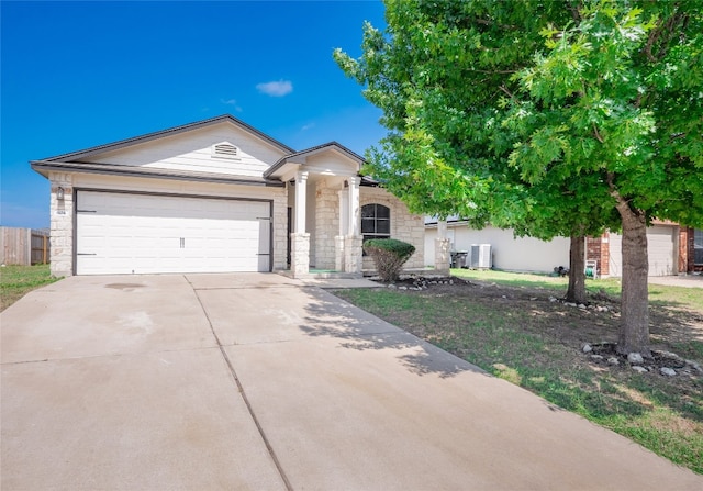 604 Creston St, Hutto, TX 78634 - view of front of house featuring driveway, a garage, stone siding, and central AC