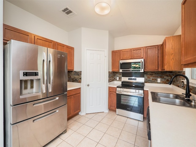 604 Creston St, Hutto, TX 78634 - kitchen featuring appliances with stainless steel finishes, a sink, light countertops, brown cabinetry, and tasteful backsplash