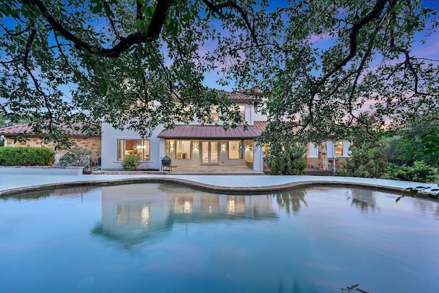 9308 Prince Charles, Austin, TX 78730 - pool at dusk featuring french doors, an outdoor pool, a patio area, and a grill