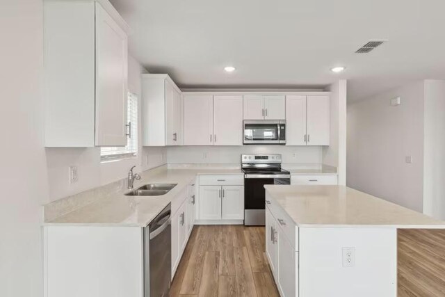 2807 Dimmit Dr, Temple, TX 76501 - kitchen featuring appliances with stainless steel finishes, a sink, light countertops, light wood-style floors, and white cabinets