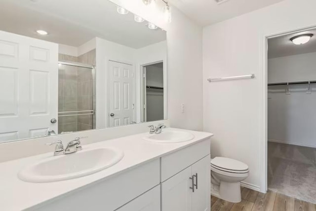 2807 Dimmit Dr, Temple, TX 76501 - bathroom with a walk in closet, double vanity, a stall shower, toilet, and wood finished floors