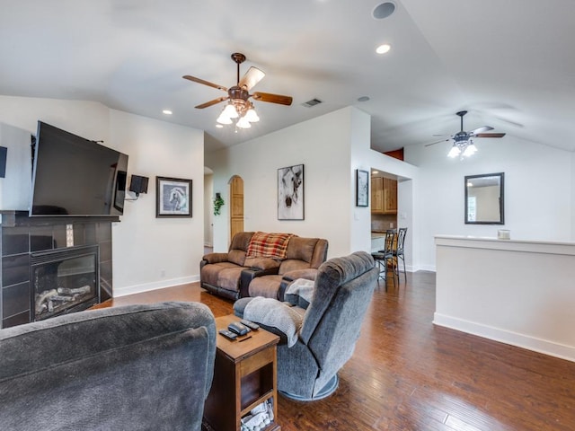 20104 Bunker Cv, Lago Vista, TX 78645 - living area featuring a ceiling fan, lofted ceiling, arched walkways, a tiled fireplace, and dark wood-style floors