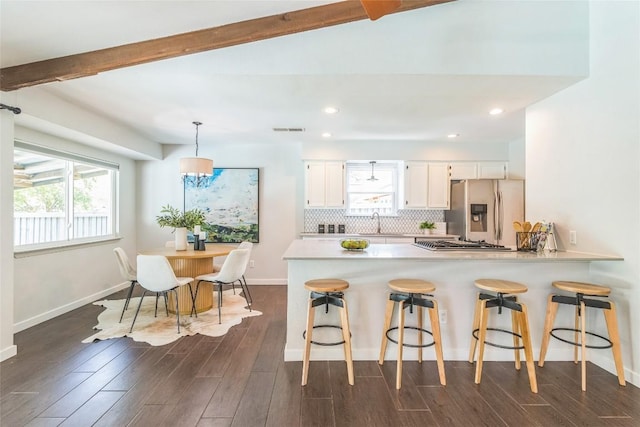 10108 Osprey Ct, Austin, TX 78750 - kitchen featuring appliances with stainless steel finishes, a peninsula, a sink, beam ceiling, and dark wood finished floors