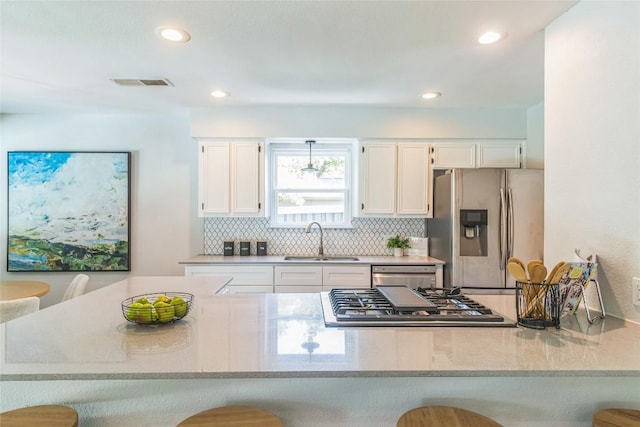 10108 Osprey Ct, Austin, TX 78750 - kitchen featuring stainless steel appliances, a sink, white cabinets, decorative backsplash, and a breakfast bar