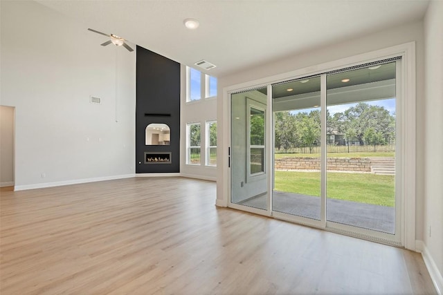 159 Fireside Rd, Austin, TX 78737 - unfurnished living room featuring light wood-type flooring, ceiling fan, a towering ceiling, and a fireplace