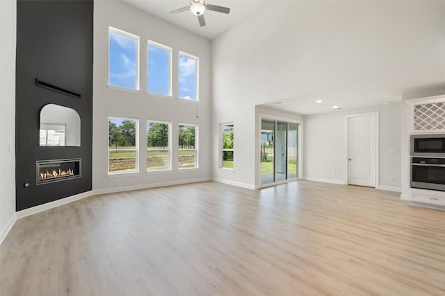 159 Fireside Rd, Austin, TX 78737 - unfurnished living room with a ceiling fan, light wood finished floors, a fireplace, and a high ceiling