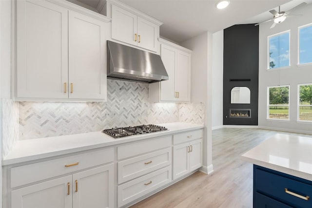 159 Fireside Rd, Austin, TX 78737 - kitchen with under cabinet range hood, stainless steel gas cooktop, ceiling fan, decorative backsplash, and light countertops